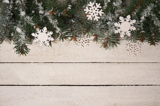 Foto witte armoedige kerstgrens met besneeuwde dennenboom, houten achtergrond met kopieerruimte