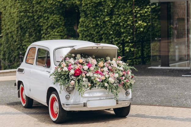 Witte auto met enorme bloemen uit de motorkap in de stad