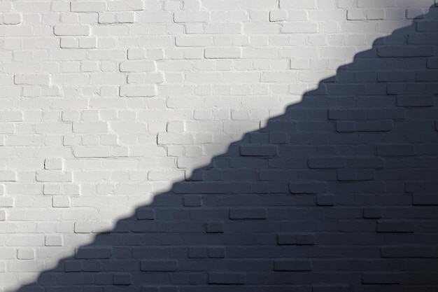 Witte bakstenen muur is verdeeld in lichte en schaduwdelen langs de diagonaal in de vorm van trappen.