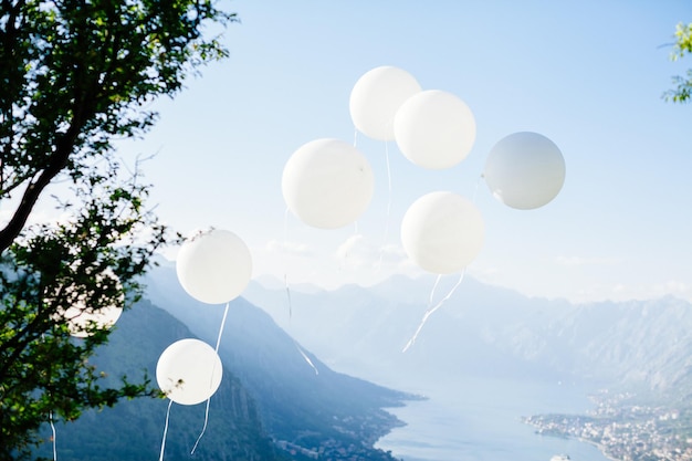 Witte ballons vliegen op blauwe hemel bergen en uitzicht op zee achtergrond