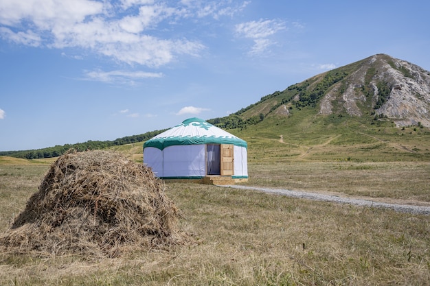 Witte bashkir yurt staat tussen een hooiberg en een berg