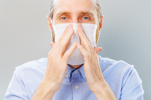 Witte, bebaarde man in blauw shirt zet een masker op van luchtverontreiniging en coronavirus Covid-19.