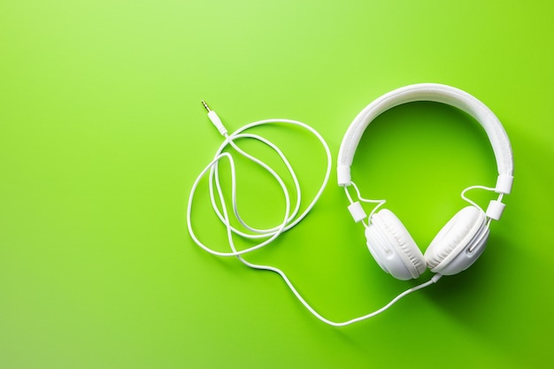Witte bedrade stereohoofdtelefoon op groene achtergrond bovenaanzicht