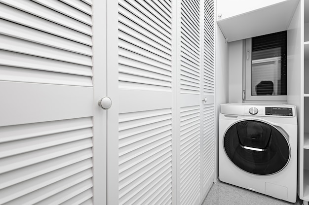 Witte bijkeuken met grote kleerkast en wasmachine in nieuw luxe appartement