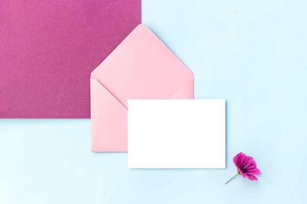 Witte blanco kaart roze envelop en bloemen Bovenaanzicht Platliggend Mockup