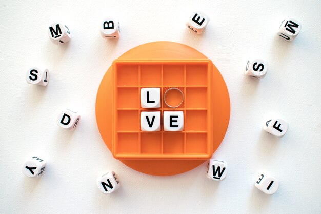 Witte blok woord liefde met zilveren trouwring op oranje doos