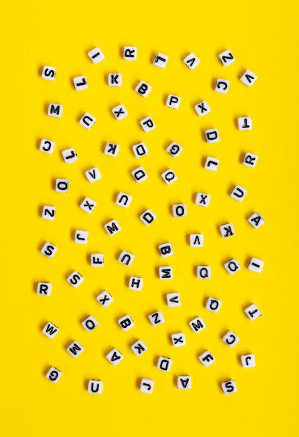 Witte blokjes met letters willekeurig verspreid op een gele achtergrond