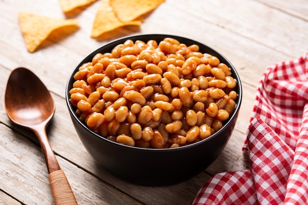 Witte bonen in tomatensaus in kom op houten tafel