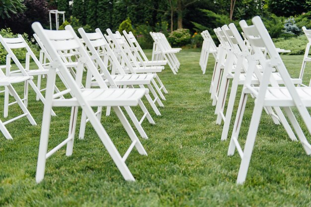 Witte bruiloft stoelen op groen gras.