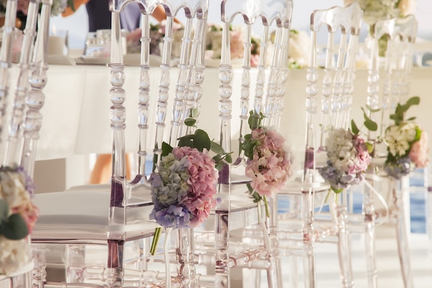 Witte bruiloft stoelen versierd met verse bloemen in restaurant met panoramisch uitzicht op zee