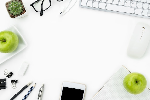 Witte bureau tafel met veel kantoorbenodigdheden eroverheen met appels.