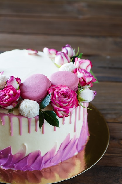 Witte cake met een roze decoratie op een houten tafel