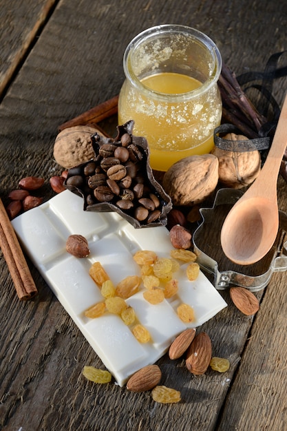 Witte chocolade met rozijnen, amandelen, walnoten, koffiebonen, de oude houten tafel.