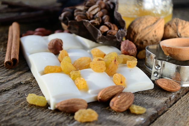 Witte chocolade met rozijnen, amandelen, walnoten, koffiebonen, de oude houten tafel.