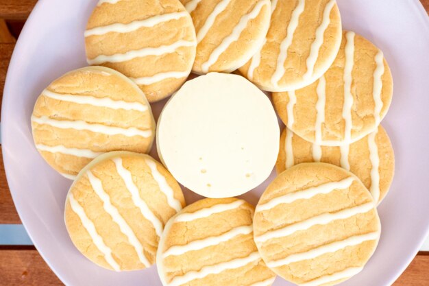 Witte chocoladekoekjes met citroen en sinaasappel op een roze bord op een café tafel