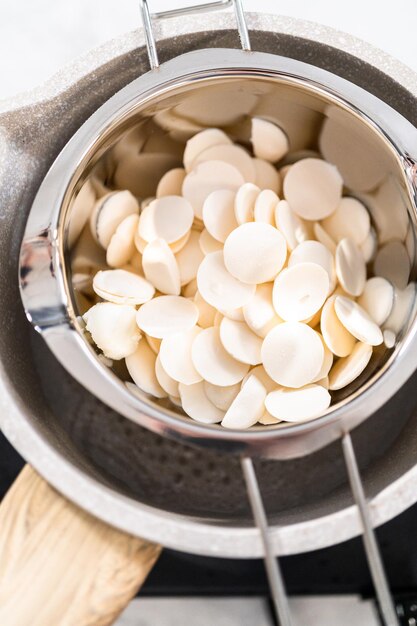 Witte chocoladeschilfers smelten in een roestvrijstalen dubbele ketel boven een kookpot met heet water