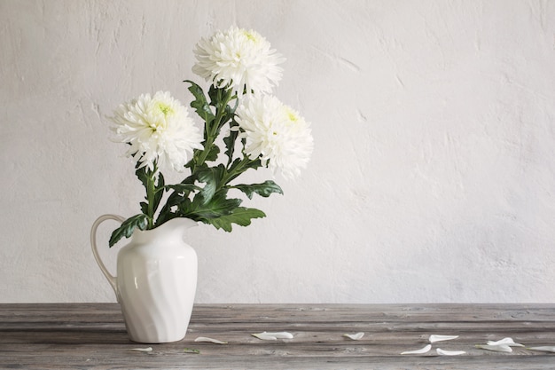 Witte chrysant in kruik op een houten tafel