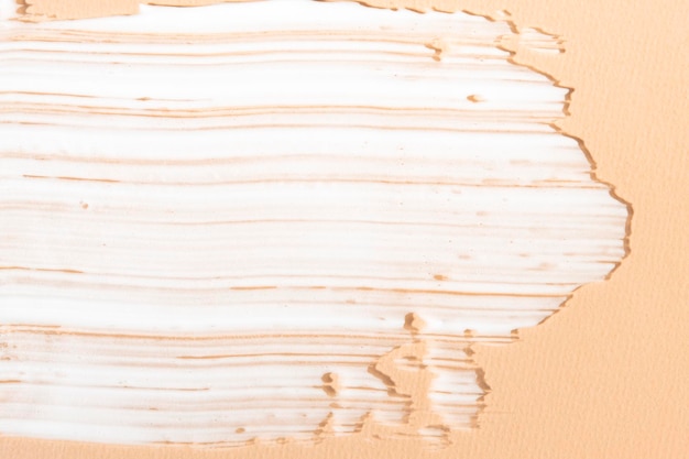 Witte cosmetische crème op een beige achtergrond close-up textuur hygiëne product vloeibare zeep huidlotion
