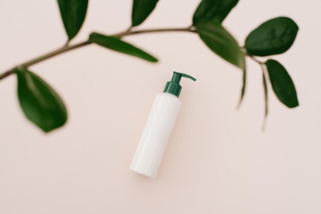 Witte cosmetische fles crème met een bovenaanzicht van de bladeren van planten een mockup van het productontwerp Natuurlijke biologische cosmetica