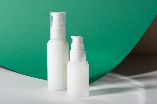 Witte cosmetische flessen met crème, gezichtsmasker op een groene achtergrond. Mockup van een vochtinbrengende crème.