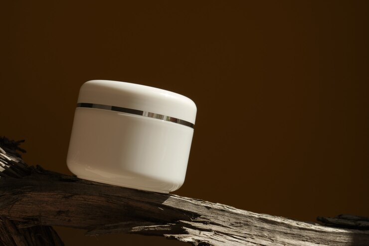 Witte cosmetische pot met room op een logboek en met harde schaduwen