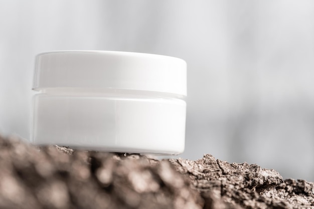 Witte cosmetische pot op boomschors
