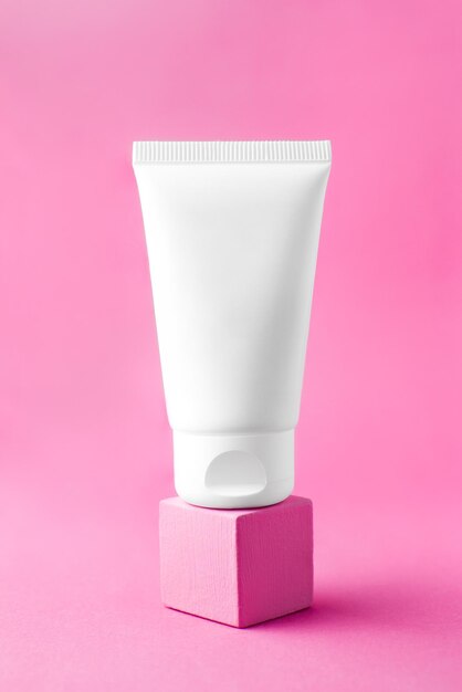 Witte crème tube mockup op vierkant podium op roze achtergrond