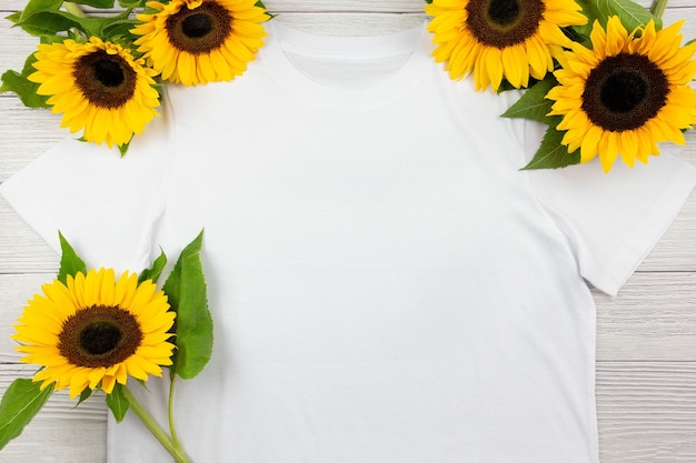 Witte dames katoenen t-shirt mockup met zonnebloemen op witte houten achtergrond. ontwerp t-shirt sjabloon, print presentatie mock up. bovenaanzicht plat lag.