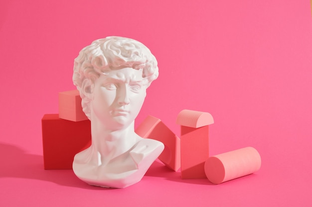 Foto witte decoratieve sculpturale buste en verschillende roze geometrische onderzetters op een roze achtergrond