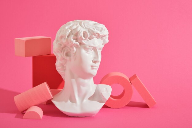 Foto witte decoratieve sculpturale buste en verschillende roze geometrische onderzetters op een roze achtergrond