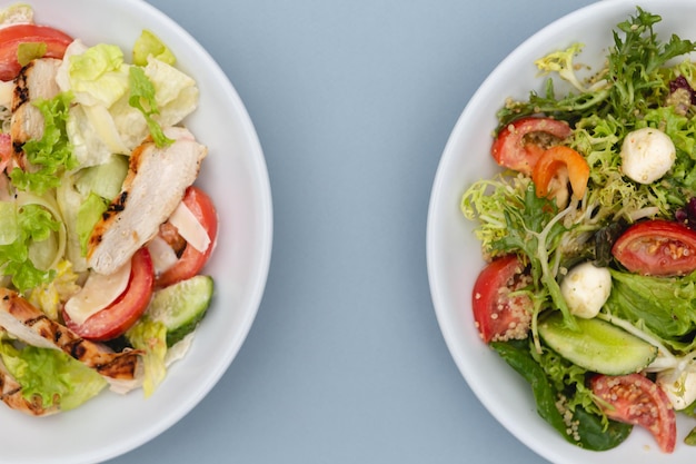 Witte diepe borden met verse salade-ingrediënten vermengd met saus op een aantrekkelijke achtergrond