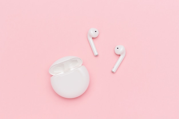 Witte draadloze Bluetooth-hoofdtelefoons en het laden van geval op roze achtergrond