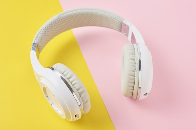Witte draadloze koptelefoon op een roze en gele achtergrond