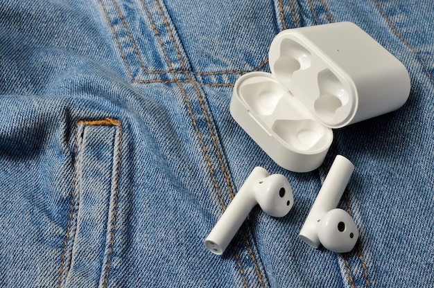 Witte draadloze stereohoofdtelefoons met een hoesje liggen op denim