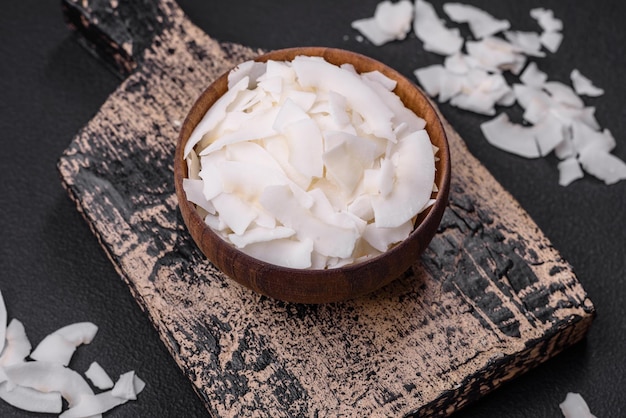 Witte droge kokosvlokken in een houten kom, bereid voor het maken van desserts