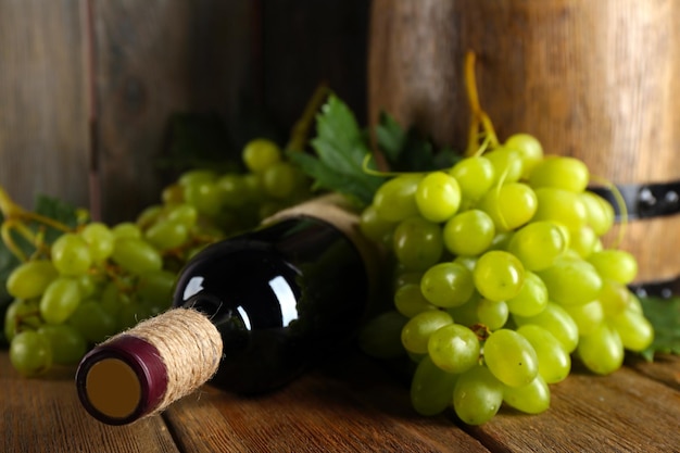 Witte druif met fles wijn op houten achtergrond