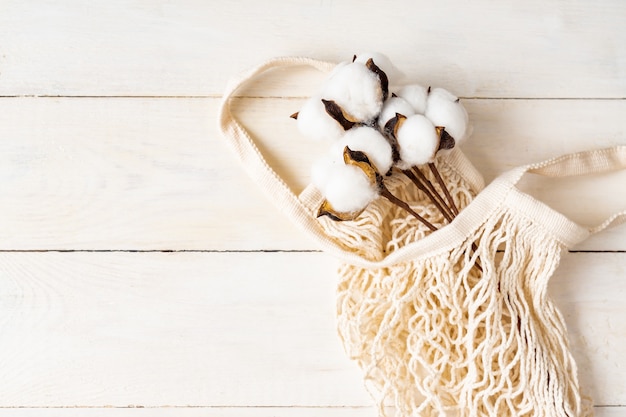 Witte eco tas mesh textuur met katoenen tak op een natuurlijke houten witte achtergrond.