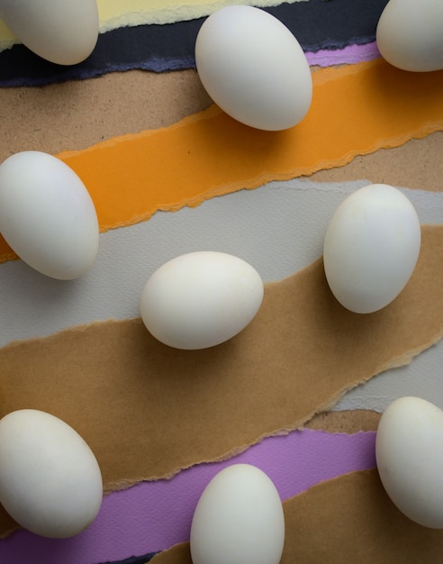 Witte eieren die plat op de grond lagen op creatieve pastel gescheurde papieren abstracte textuurachtergrond