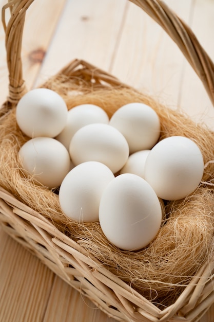 Witte eieren in de mand verspreid over houten tafel. de producten van de boerderij.