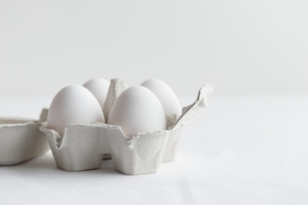 Witte eieren in een eierdoos die op een witte tafel staat