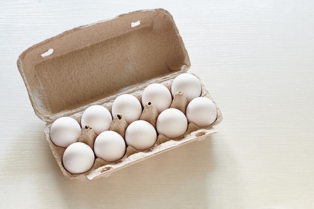 Witte eieren in papieren eierdoos Kippeneieren Kartonnen eierdoos op de witte tafel in de zon met schaduw Bovenaanzicht