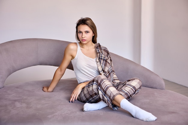 Witte elegante vrouw in pyjama zit op bed