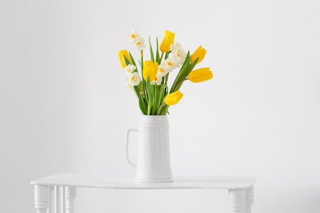 Witte en gele Lentebloemen in vaas op witte achtergrond
