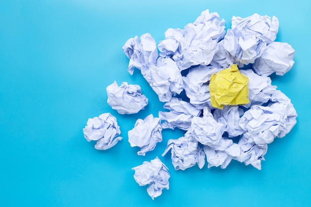 Witte en gele verfrommeld papier ballen op een blauwe achtergrond. Bovenaanzicht