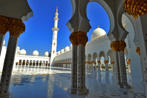 Witte en gouden islamitische architectuur met kolonnade en koepels en minaret