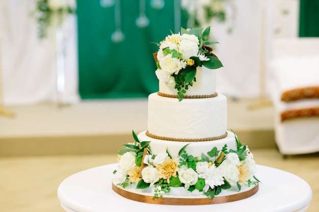 Witte en groene bruidstaart met bloemen bij de receptie