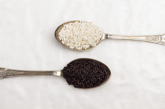 Witte en zwarte rijst in metalen lepels. Plat leggen