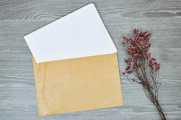 Witte envelop mockup blanco sjabloon met gele gypsophila bloem op houten grijze tafel