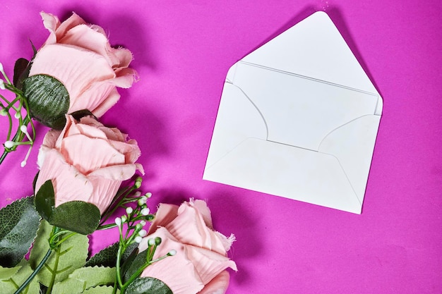 Witte envelop mockup lege sjabloon met roze roze bloem op roze achtergrond