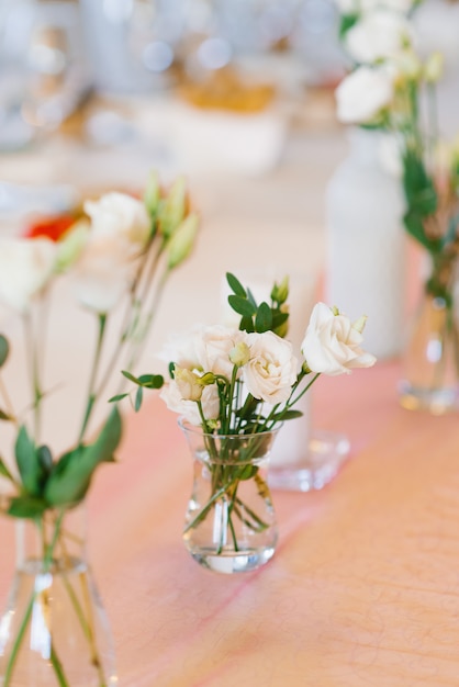 Witte eustoma bloemen in een glazen vaas staat op een tafel. Bruiloft banket tafel